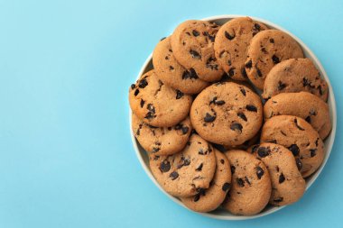 Açık mavi arka planda bir kase lezzetli çikolatalı kurabiye, üst manzara. Metin için boşluk