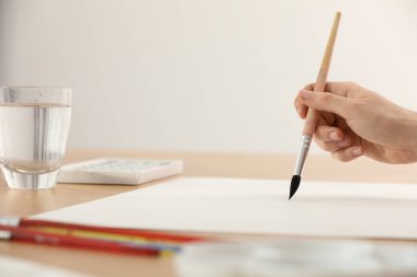 Ahşap masadaki fırçalı kadın, yakın çekim ve yazı için yer. Suluboya sanat eserleri