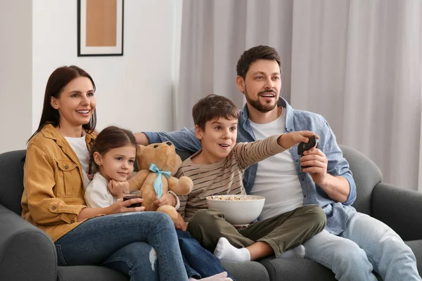 家庭でテレビを見て幸せな家族 遠隔操作でチャンネルを変える息子 — ストック写真