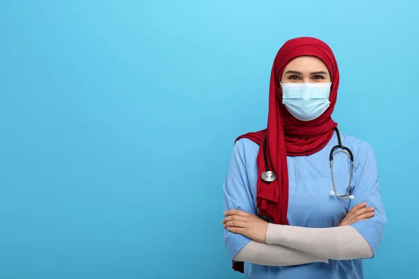 Muslimka Nosí Hidžáb Lékařskou Uniformu Ochrannou Masku Světle Modrém Pozadí — Stock fotografie