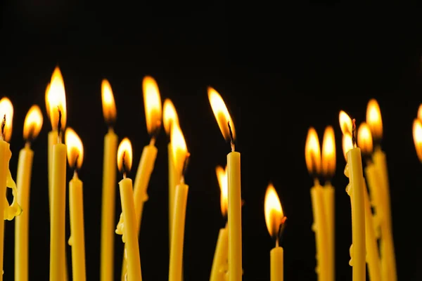 许多教堂的蜡烛在黑色背景上燃烧 — 图库照片