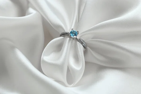 Beyaz Kumaşın Üzerinde Açık Mavi Mücevher Olan Güzel Bir Yüzük — Stok fotoğraf