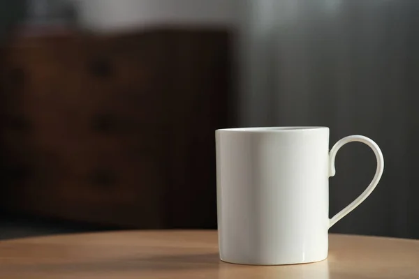 White mug on wooden table indoors. Mockup for design