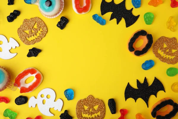 Rahmen Aus Leckeren Bonbons Und Halloween Dekorationen Auf Gelbem Hintergrund — Stockfoto