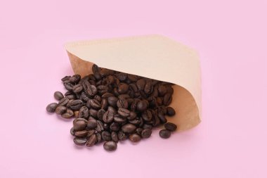 Soluk pembe arka planda fasulye ile kağıt kahve filtresi