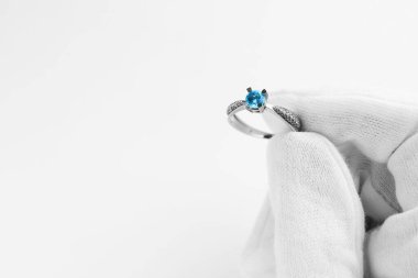 Kuyumcu beyaz arka planda topaz yüzüğü tutuyor, yakın plan. Metin için boşluk