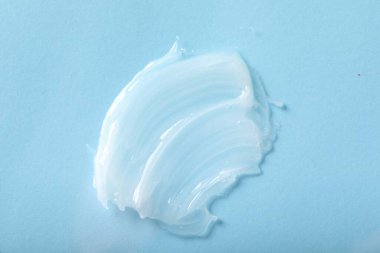 Smear of ointment on light blue background, top view