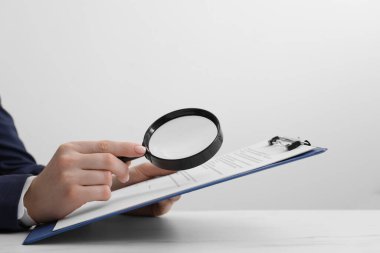 Beyaz masadaki kadın belgeye büyüteçle bakıyor, yakın plan. Konsept aranıyor