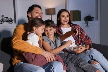 Mutlu aile akşamları evde televizyon seyrediyor.