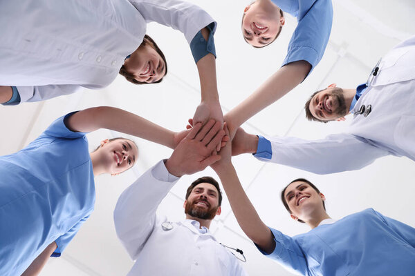 Team of medical doctors putting hands together indoors, bottom view
