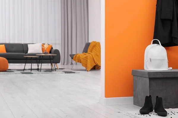 带着背包和鞋子的Pouf靠近橙色的墙壁 在时尚的房间里 文字的空间 室内设计 — 图库照片