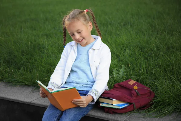 Cute Little Girl Plecakiem Czytania Podręcznika Ulicy Miasta — Zdjęcie stockowe