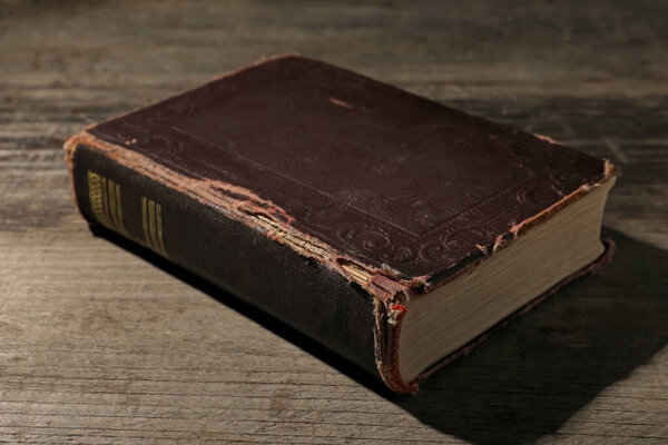 One old hardcover book on wooden table, closeup