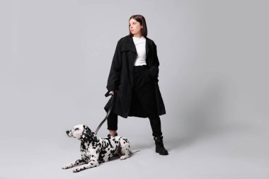 Açık gri arka planda sevimli Dalmaçyalı köpeği olan güzel genç bir kadın. Sevimli hayvan