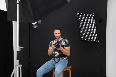 Modern fotoğraf stüdyosunda kamerası olan genç profesyonel fotoğrafçı.
