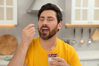 Yakışıklı adam mutfakta lezzetli yoğurt yiyor.