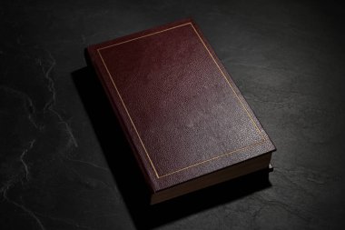 One old hardcover book on black textured table