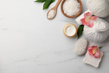 Flat lay composition with spa products and flowers on white marble table. Space for text