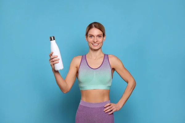 ライトブルーの背景に魔法瓶付きスポーツ女性 — ストック写真