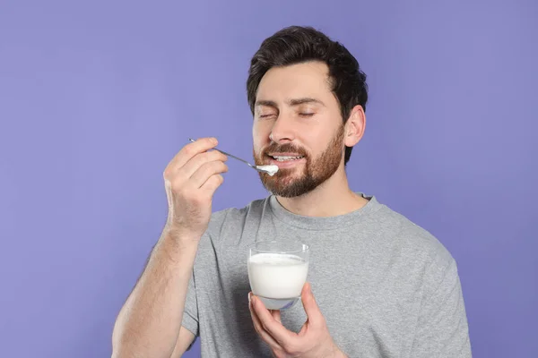 Snygg Man Äter Läcker Yoghurt Violett Bakgrund — Stockfoto