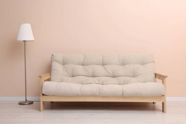 Comfortable sofa and stylish lamp near beige wall indoors