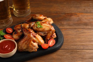 Biralı fincanlar, ahşap masada pişmiş tavuk kanadı ve sos. Metin için boşluk