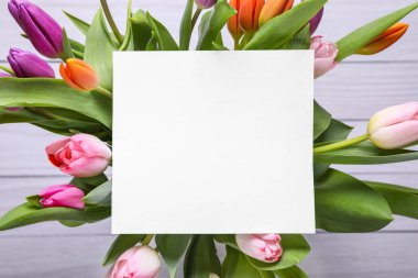 Beyaz ahşap arka planda boş kartı olan güzel bir lale buketi. Doğum günü kutlaması