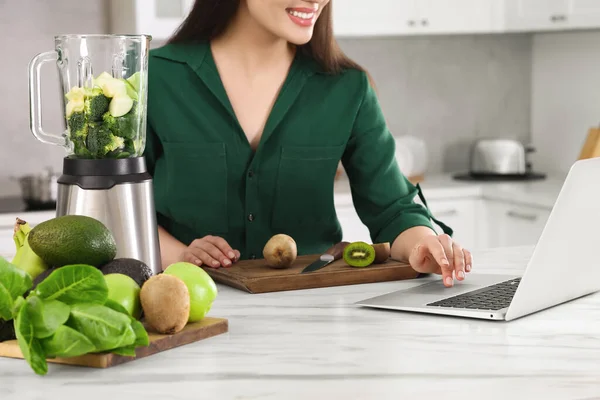 Jovem Mulher Usando Laptop Enquanto Prepara Smoothie Mesa Branca Cozinha — Fotografia de Stock