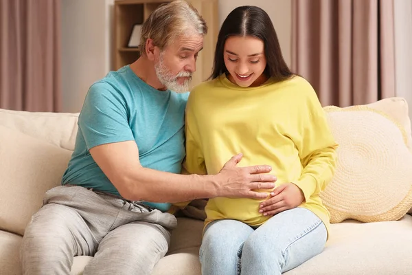 Happy pregnant woman spending time with her father at home. Grandparents\' reaction to future grandson