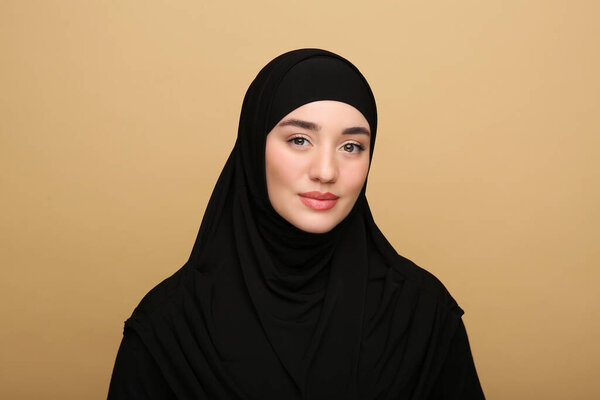 Portrait of Muslim woman in hijab on beige background