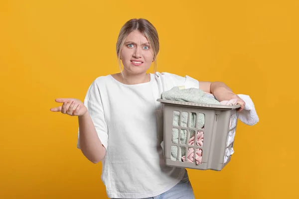 Junge Frau Mit Korb Voller Wäsche Auf Orangefarbenem Hintergrund — Stockfoto