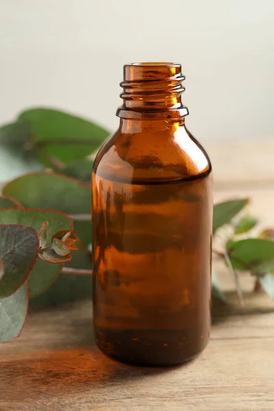 Eine Flasche Ätherisches Eukalyptusöl Und Blätter Auf Dem Holztisch — Stockfoto