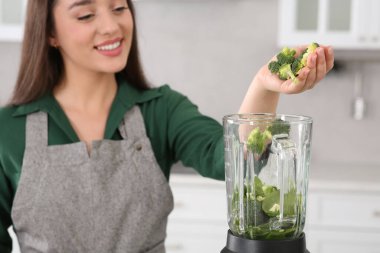 Mutfakta smoothie için malzemelerle karıştırıcıya brokoli ekleyen kadın, eline odaklan.
