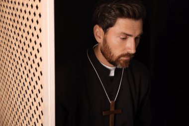 Günah çıkarma kabininde cübbe giyen Katolik rahip.