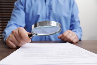 Ahşap masadaki adam belgeye büyüteçle bakıyor, yakından. Konsept aranıyor