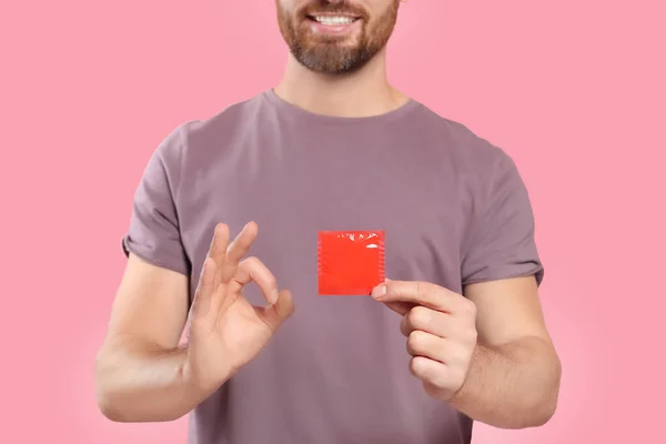 Чоловік Презервативом Показує Нормальний Жест Рожевому Тлі Крупним Планом Безпечний — стокове фото