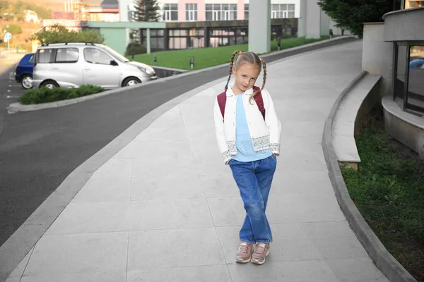 Cute little girl with backpack on city street. Space for text