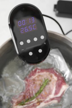 Sous vide ocağı ve elektrikli süpürge ile paketlenmiş et masanın üstünde, yakın plan. Termal daldırma tirajı
