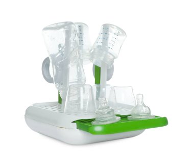 Açık gri masada beyaz arka planda kısırlaştırmadan sonra bebek şişeleri ve meme uçları olan kurutucu.