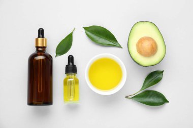 Temel yağ, taze kesilmiş avokado ve beyaz arka planda yapraklar.