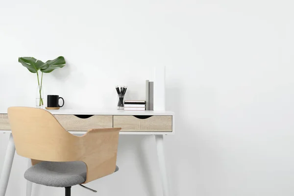Comfortable workplace with white desk near wall. Space for text