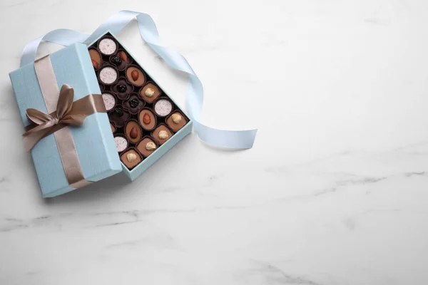 Otevřená Krabička Lahodných Čokoládových Bonbónů Světle Modrá Stuha Bílém Mramorovém — Stock fotografie