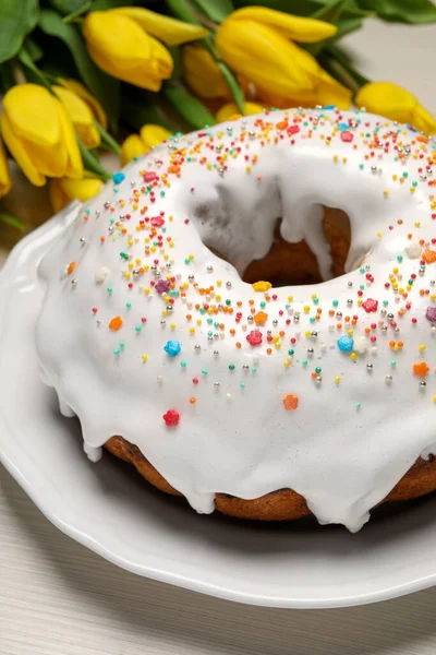 stock image Easter cake with sprinkles and tulips on white wooden table, closeup