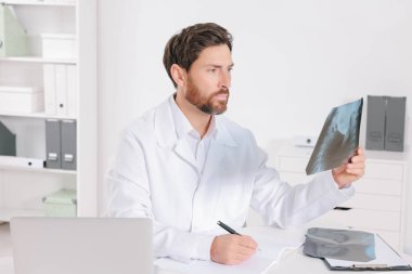 Hastanede MRI taramasından çıkan sonuçları yazan doktor.