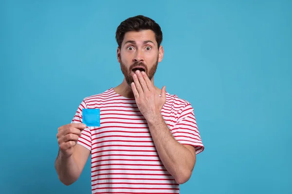 Hombre Emocional Sosteniendo Condón Sobre Fondo Azul Claro Sexo Seguro — Foto de Stock