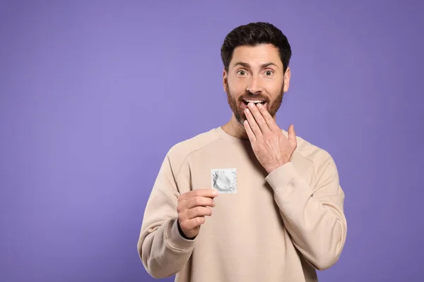 Emotional Man Holding Condom Purple Background Space Text Safe Sex — Stock Photo, Image