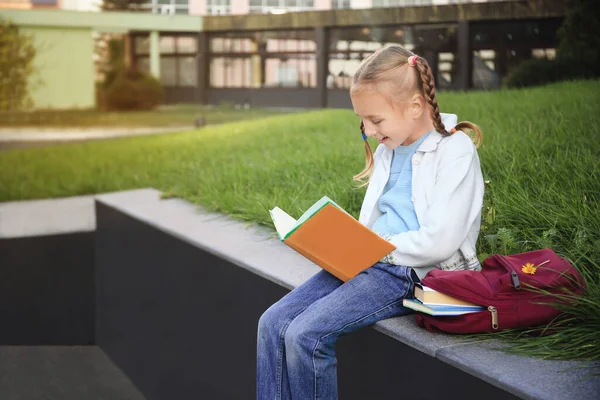 Schattig Klein Meisje Met Een Rugzak Die Schoolboek Leest Straat — Stockfoto