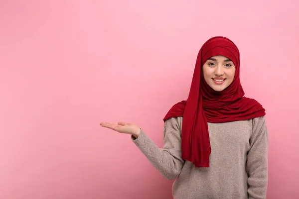 Tesettürlü Müslüman Kadın Pembe Arka Planda Bir Şeye Işaret Ediyor — Stok fotoğraf