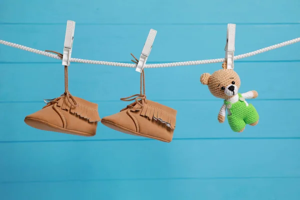 在浅蓝色木墙的衬托下 用晾衣绳擦干可爱的婴儿鞋和钩针玩具 — 图库照片