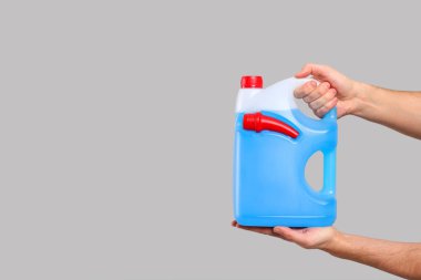 Açık gri arka planda mavi sıvılı teneke kutu tutan adam, yakın plan. Metin için boşluk